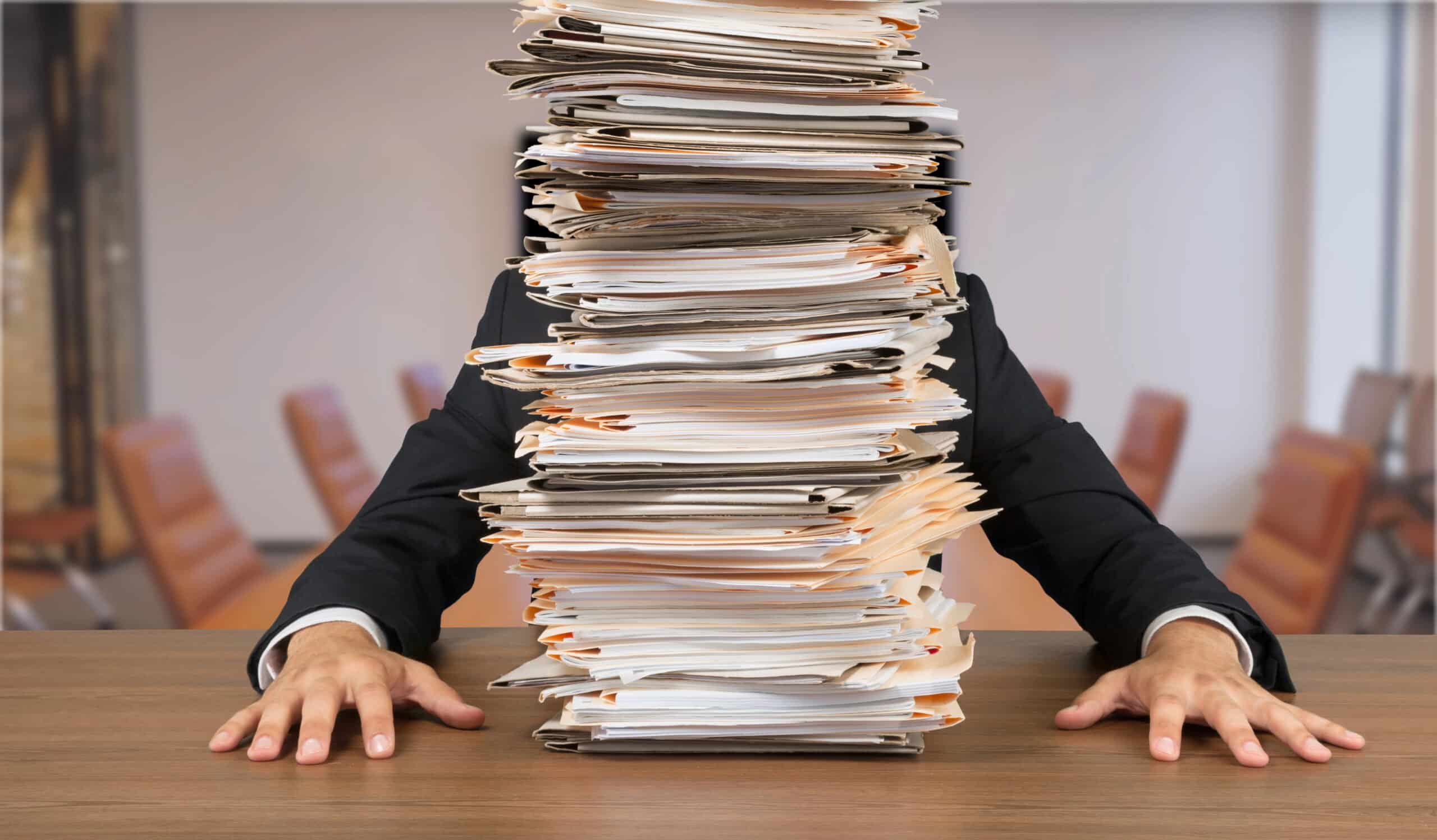 Overwhelmed office worker buried under paperwork, illustrating the chaos of poor data management inefficiencies.  