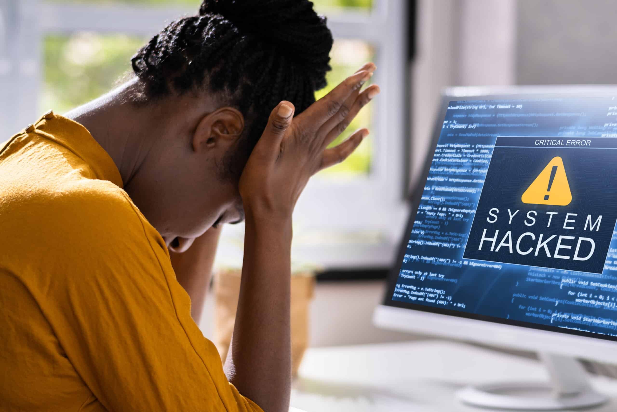 woman sitting at desk looking stressed because her computer got hacked 